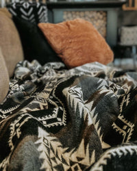 Gray and brown alpaca wool blanket on couch in a home with pillows in background