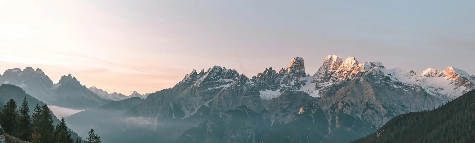 Mountain range with snow-capped peaks and misty valleys.